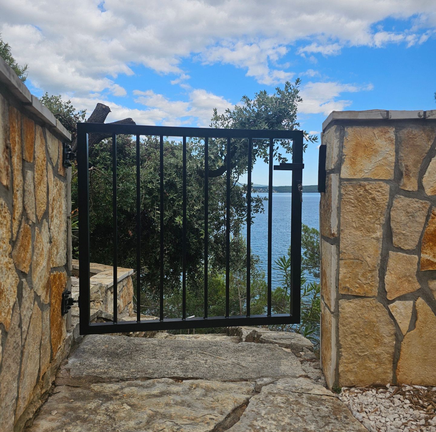 Modernes Eingangstor mit integrierter Beleuchtung und Steinpfeilern