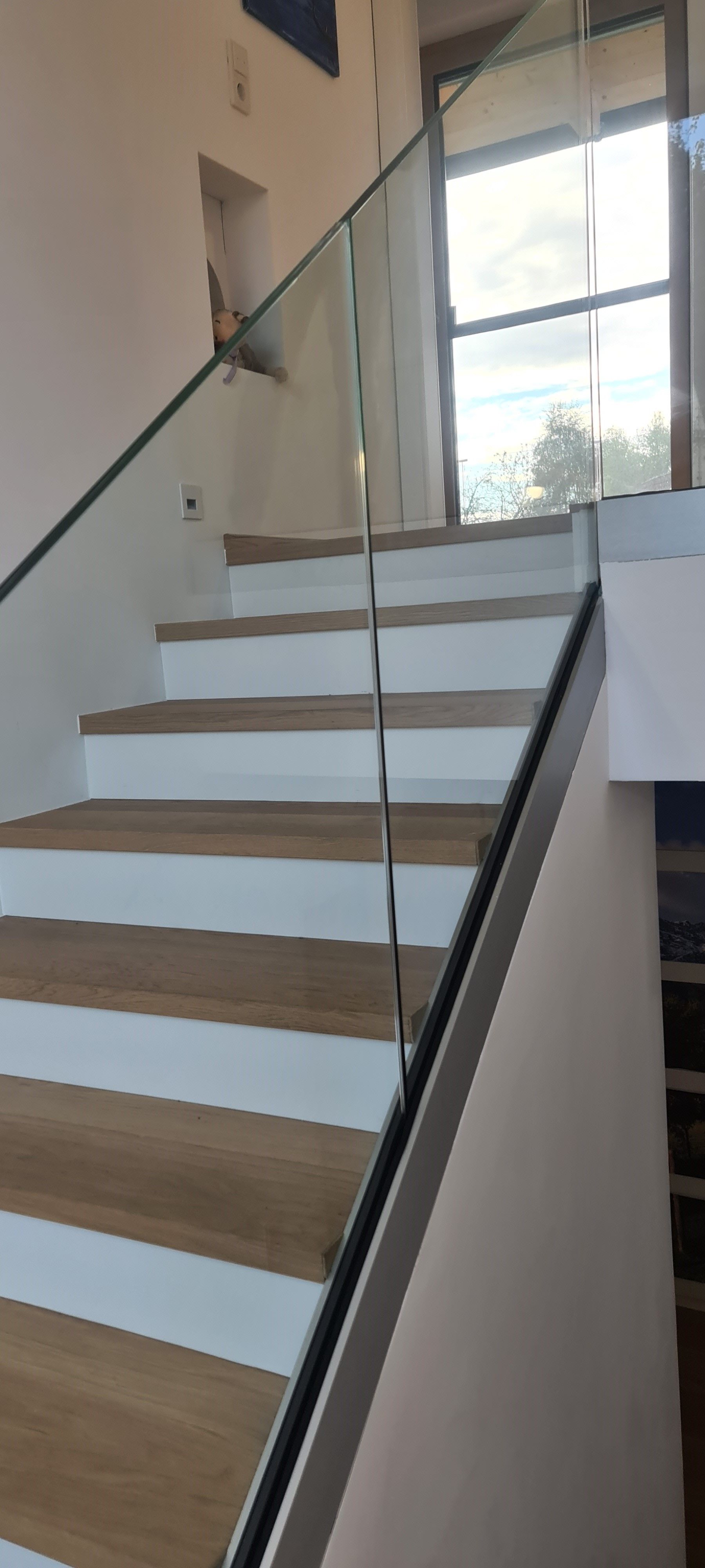 Moderne Holztreppe mit elegantem Glasgeländer und Edelstahlhandlauf in offenem Wohnbereich