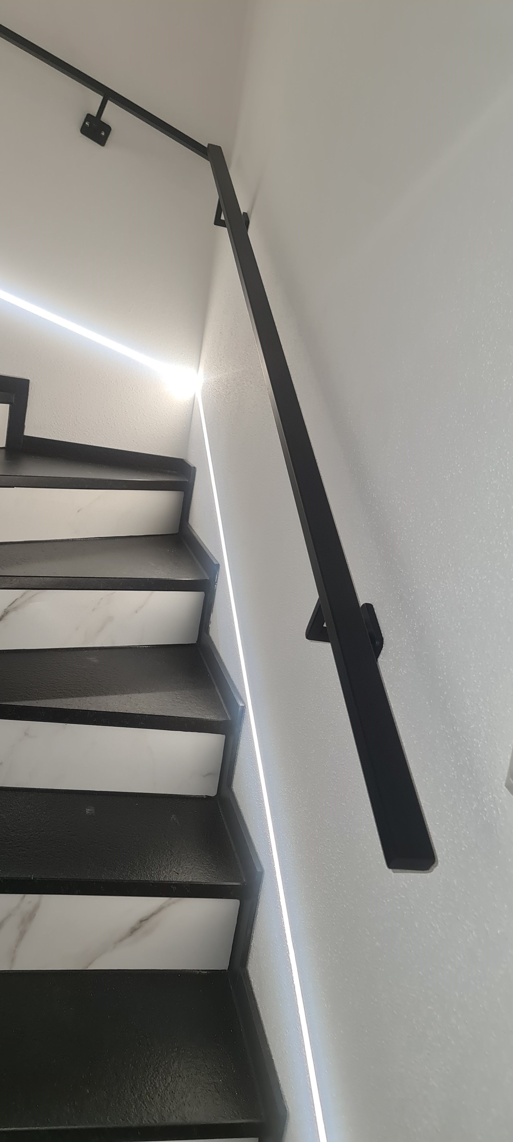 Eleganter anthrazitfarbener Handlauf mit integrierter LED-Beleuchtung im Treppenhaus